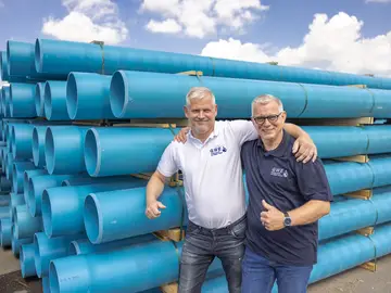 Two GWE employees laugh arm in arm into the camera.